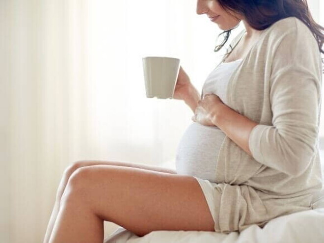 Mulher grávida sentada com uma caneca na mão