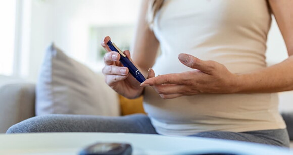 Gestante usando aparelho em formato de caneta para medir seu nível de glicose.