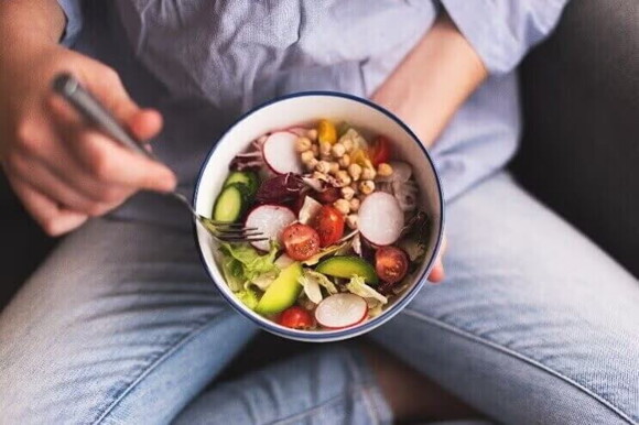 mulher comendo vegetais e alimentos ricos em ácido fólico